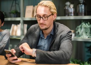 man holding a phone and looking at his watch